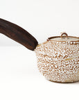 Ceramic teapot with a wooden handle on a white background, back view