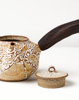 Ceramic teapot with a wooden handle on a white background, front view with lid off