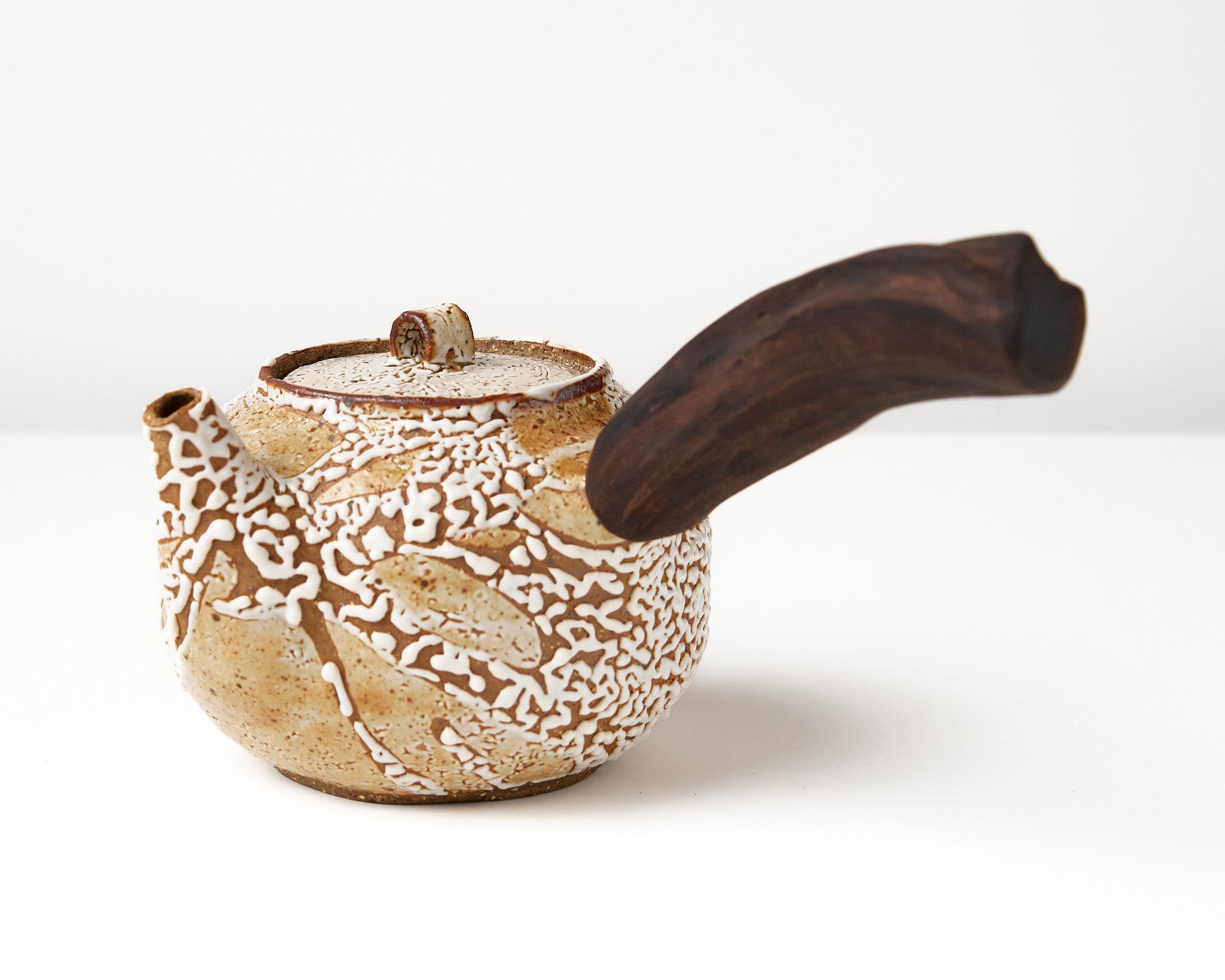 Ceramic teapot with a wooden handle on a white background, angled view