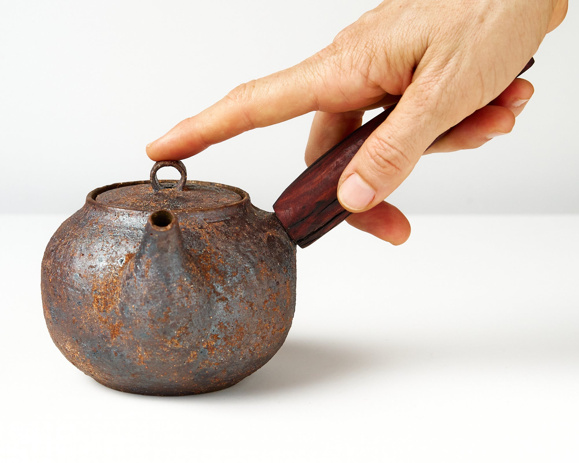 side handle tea pot with wooden handle on white background, front view with hand to show scale